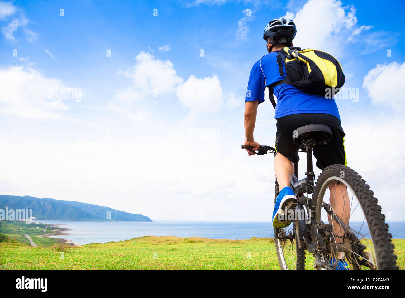 Jeune homme assis sur un vélo de montagne et à l'océan Banque D'Images