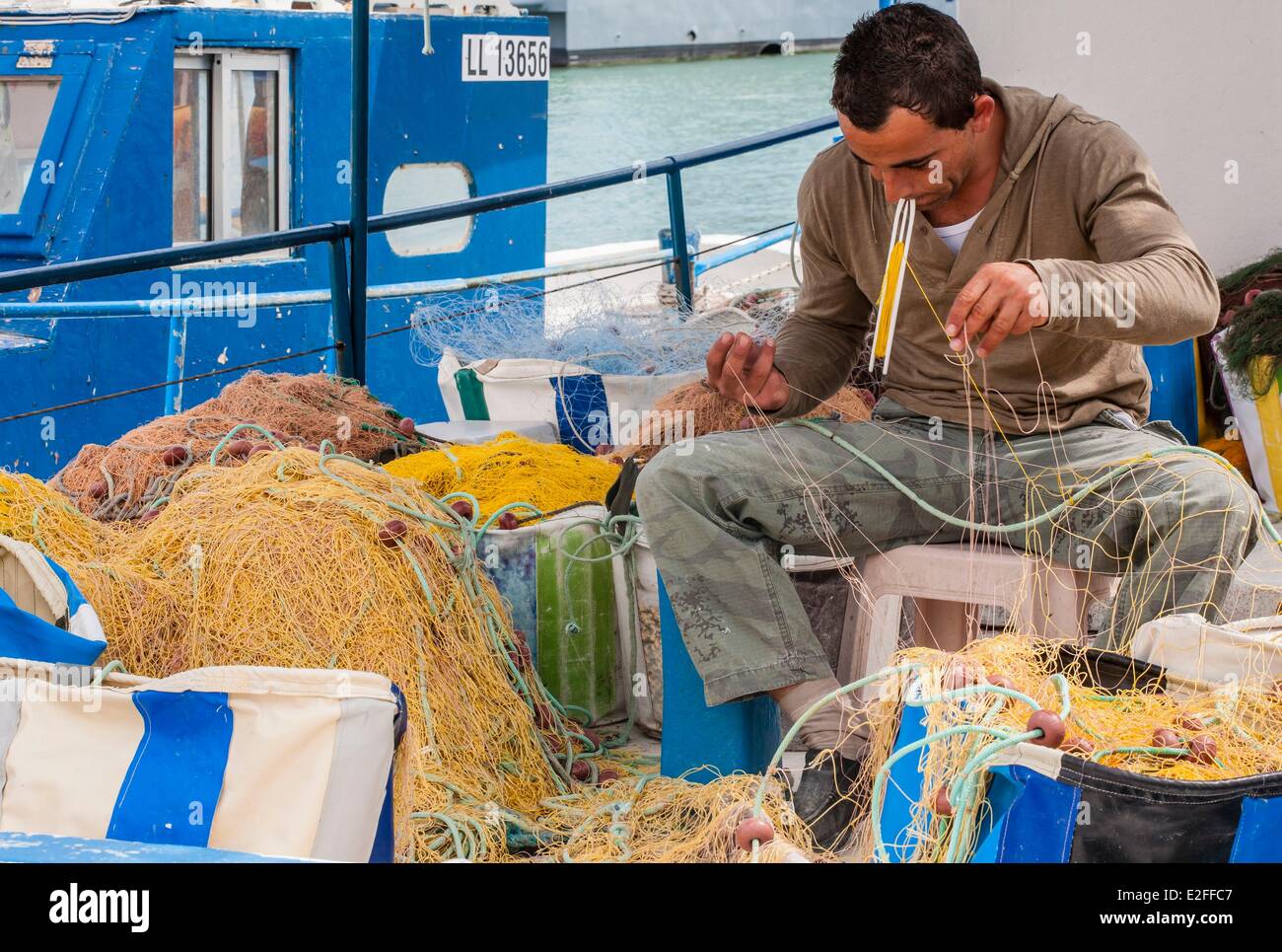 Chypre, Lakki (Latsi), port de pêche, pêcheur réparant ses filets Banque D'Images