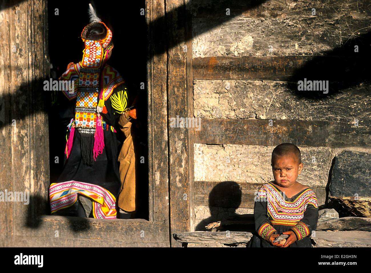Vallées Kalash Khyber Pakhtunkhwa au Pakistan vallée peu Bumburet fille Kalash entrant dans sa maison, laissant sa petite sœur assis avant l'entrée Banque D'Images