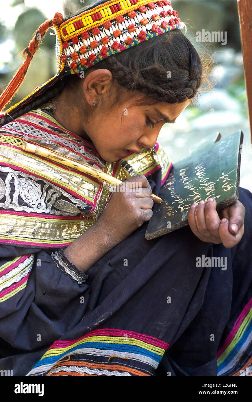 Vallées Kalash Khyber Pakhtunkhwa au Pakistan Bumburet valley school de brun village petite lycéenne Kalash écrit sur son petit tableau noir à l'aide d'un bâton trempé dans la boue liquide Banque D'Images