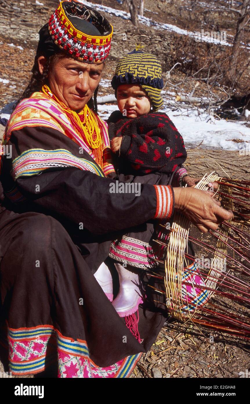Le Pakistan Khyber Pakhtunkhwa vallées Kalash Kalash valley Bumburet femme travaillant panier traditionnel travailler avec un enfant sur les genoux Banque D'Images