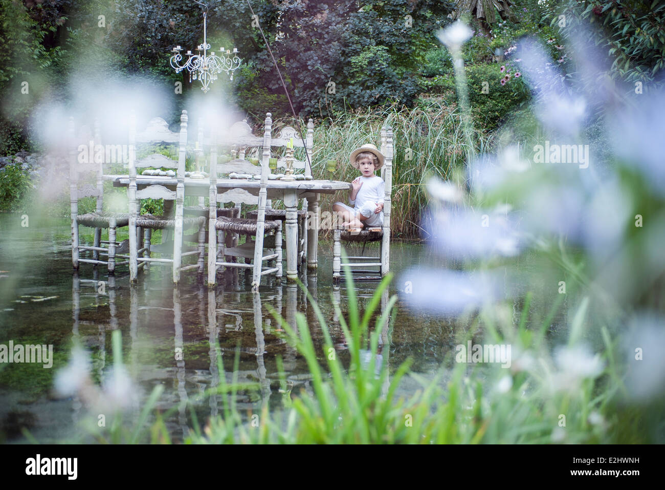 Petit garçon assis à table à manger flottant sur le lac de Banque D'Images