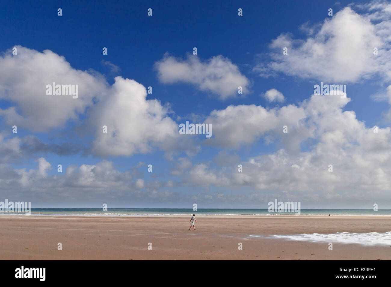 Big Sky avec les nuages au-dessus de la longue plage de sable de Port Eynon Bay. Un promeneur solitaire en regardant vers la mer. Banque D'Images