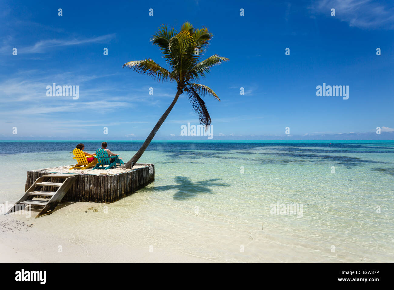 Touristes se relaxant sur des chaises de plage au bord de l'eau dans la station des Caraïbes au Belize Banque D'Images