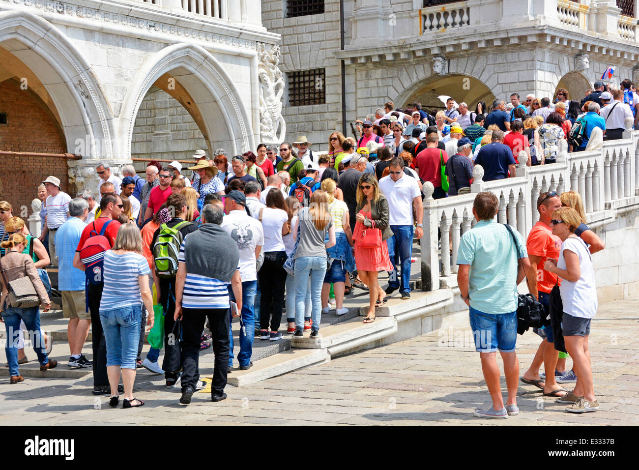 Foules touristes d'été personnes traversant le pont de pierre aux coins historiques Palais des Doges et nouvelle prison à côté du canal étroit de Venise Vénétie Italie Banque D'Images