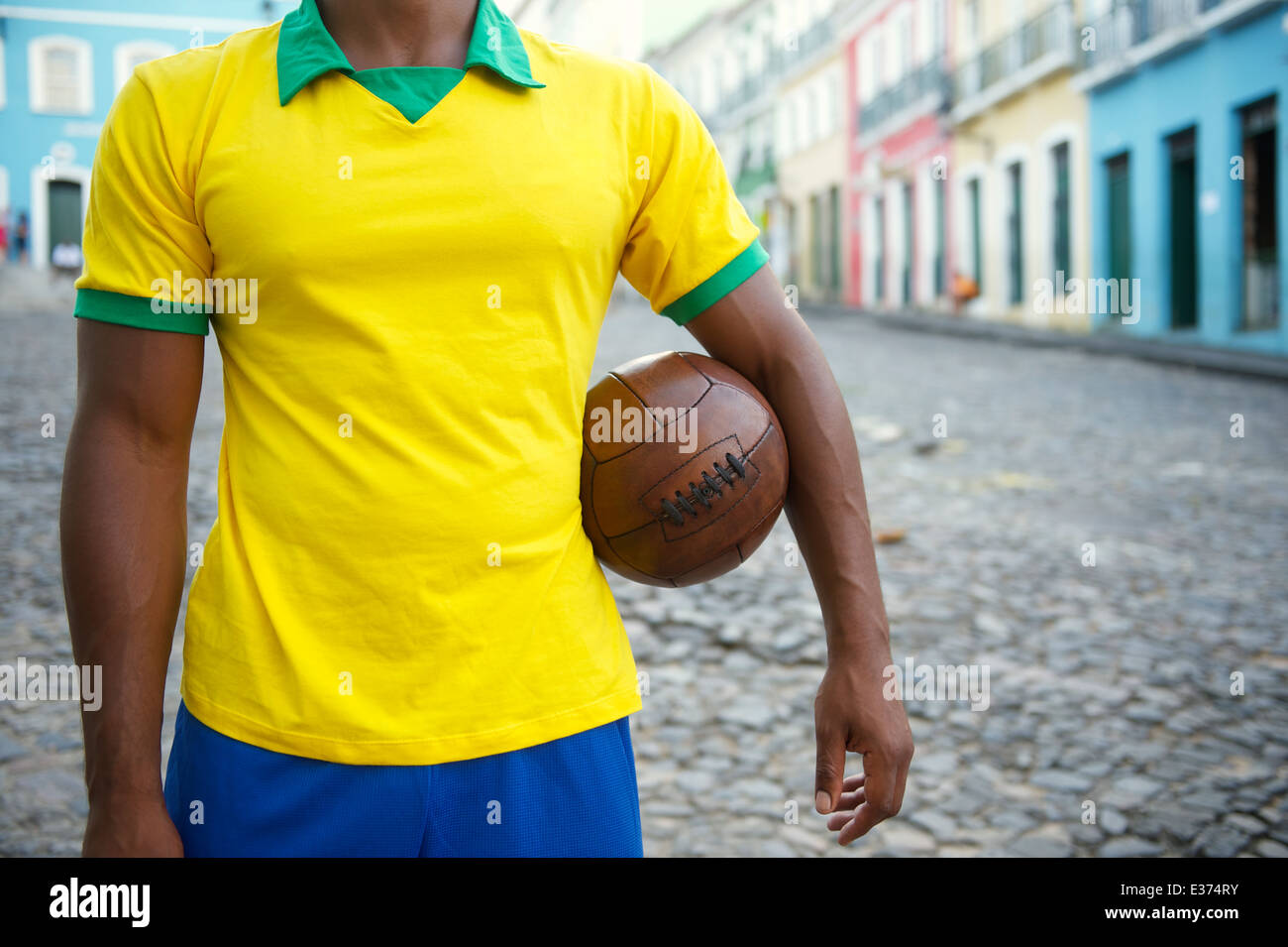 Brazilian soccer player debout sur la rue coloniale Bahia Pelourinho Salvador avec football vintage Banque D'Images
