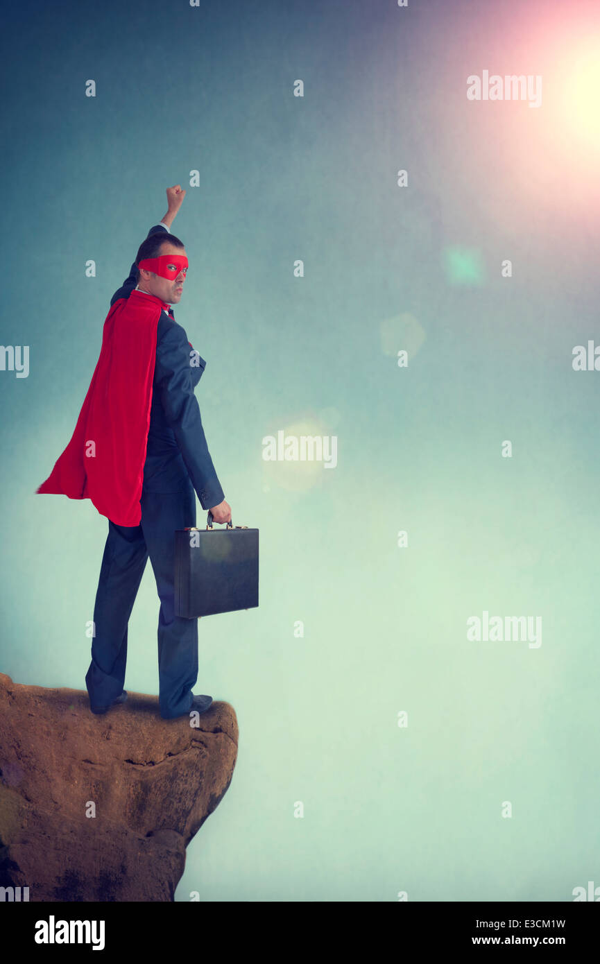 Superhero businessman debout sur une falaise, le poing de pompage Banque D'Images
