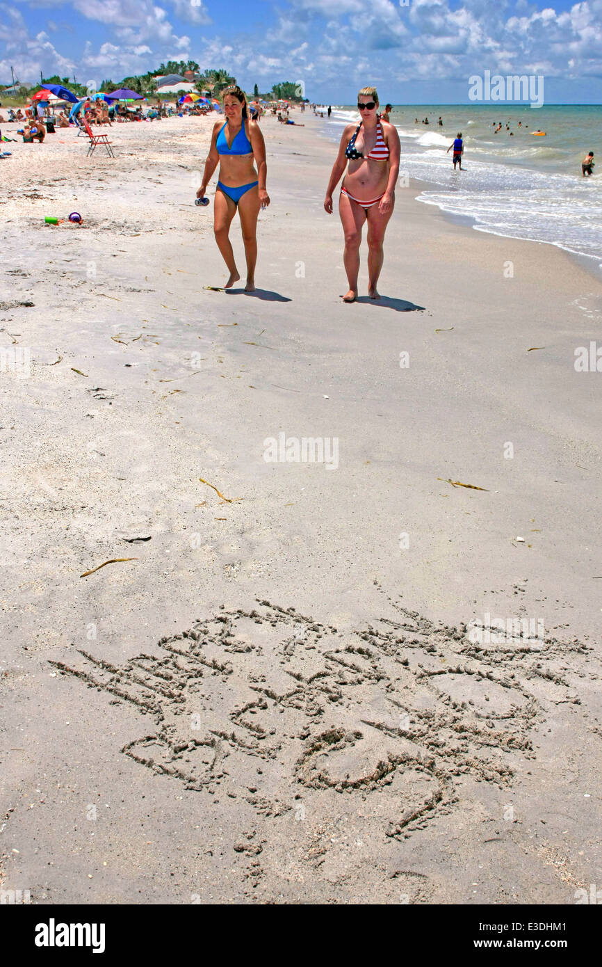 Une femme enceinte et son ami marche sur la plage en Floride où quelqu'un a écrit un message d'anniversaire Banque D'Images