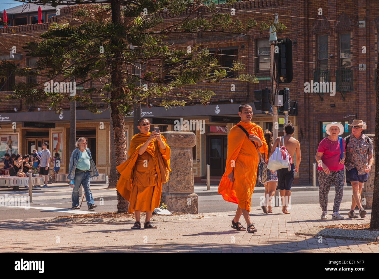 Les moines bouddhistes, marchant à travers Manly, Sydney, l'un prend une photo sur son téléphone. Banque D'Images