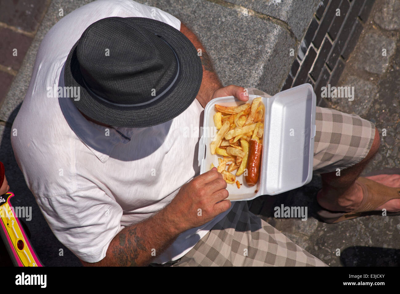 En juin, en regardant l'homme manger des saucisses et des chips à Poole Quay, Dorset, au Royaume-Uni Banque D'Images