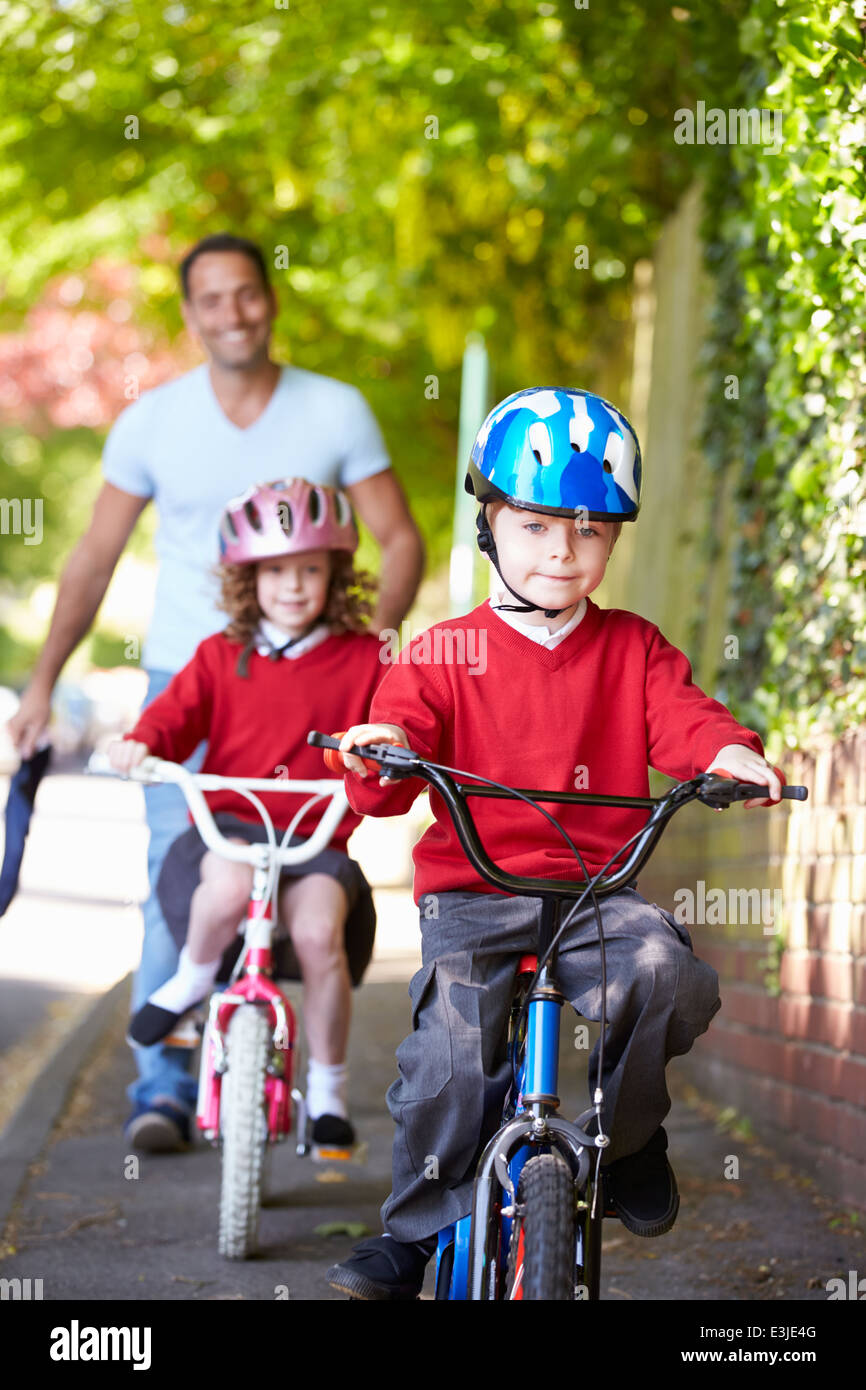 Les enfants faire du vélo sur le chemin de l'école avec le Père Banque D'Images