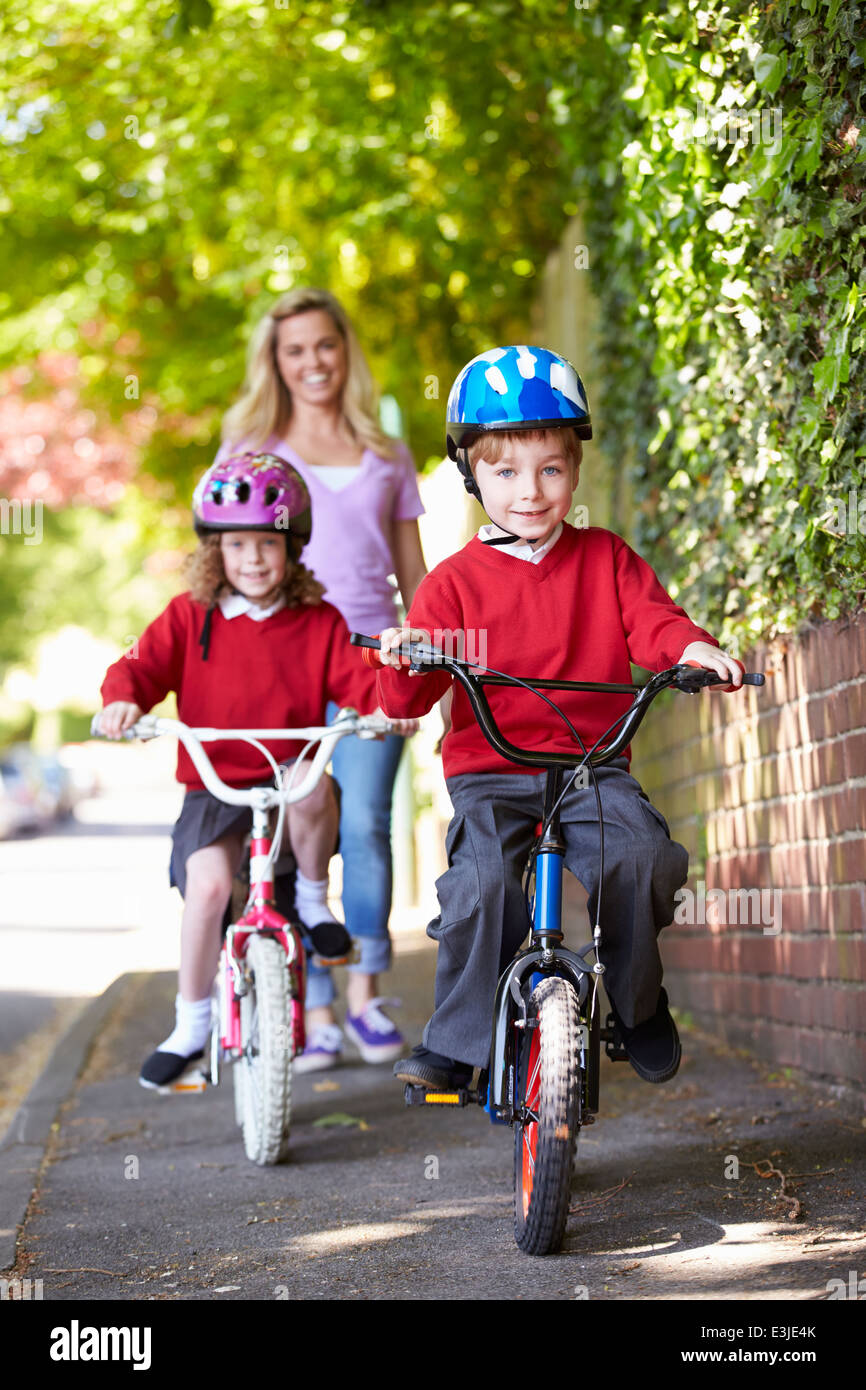 Les enfants faire du vélo sur le chemin de l'école avec la mère Banque D'Images
