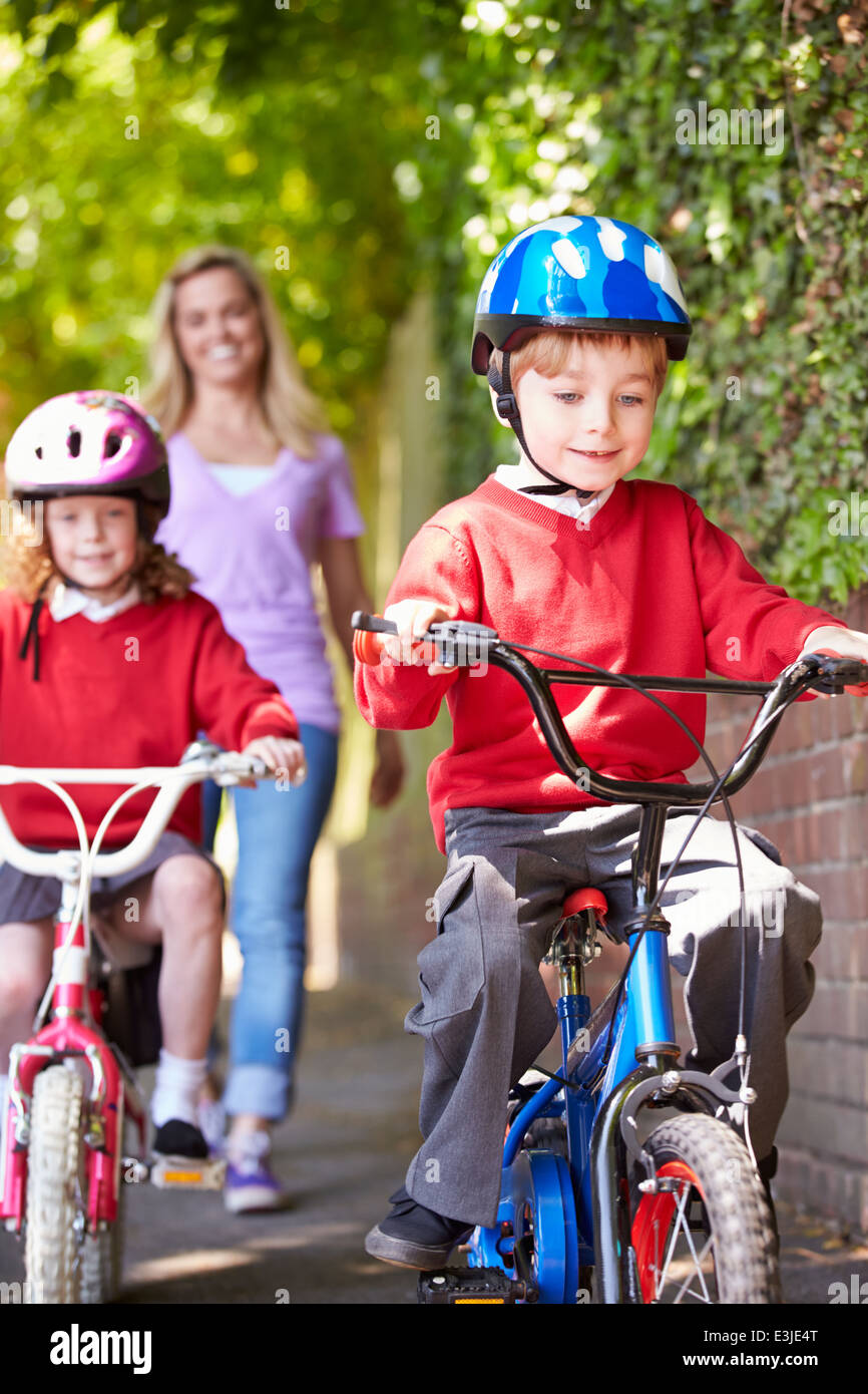 Les enfants faire du vélo sur le chemin de l'école avec la mère Banque D'Images