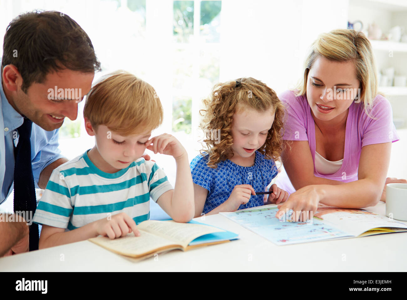 Les parents d'aider les enfants à faire leurs devoirs dans la cuisine Banque D'Images