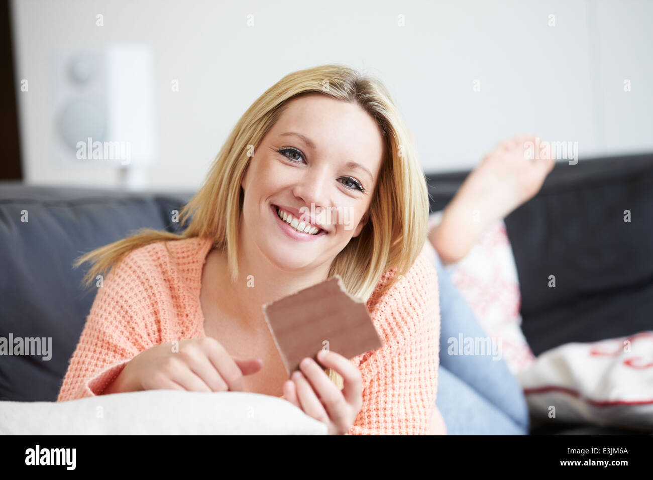 Teenage Girl Eating Barre de chocolat à la maison Banque D'Images