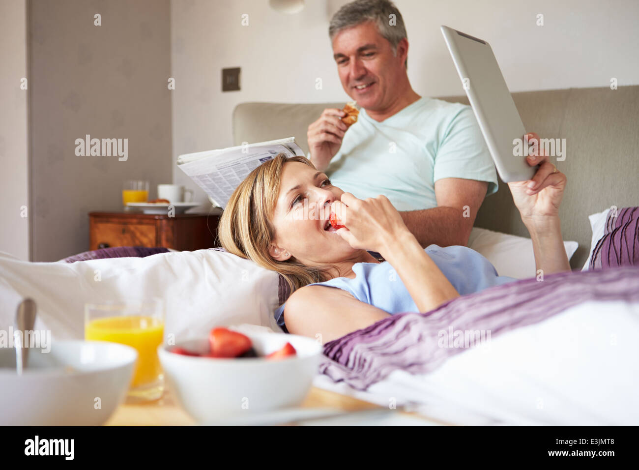 Couple Eating Breakfast In Bed avec papier et digital Tablet Banque D'Images