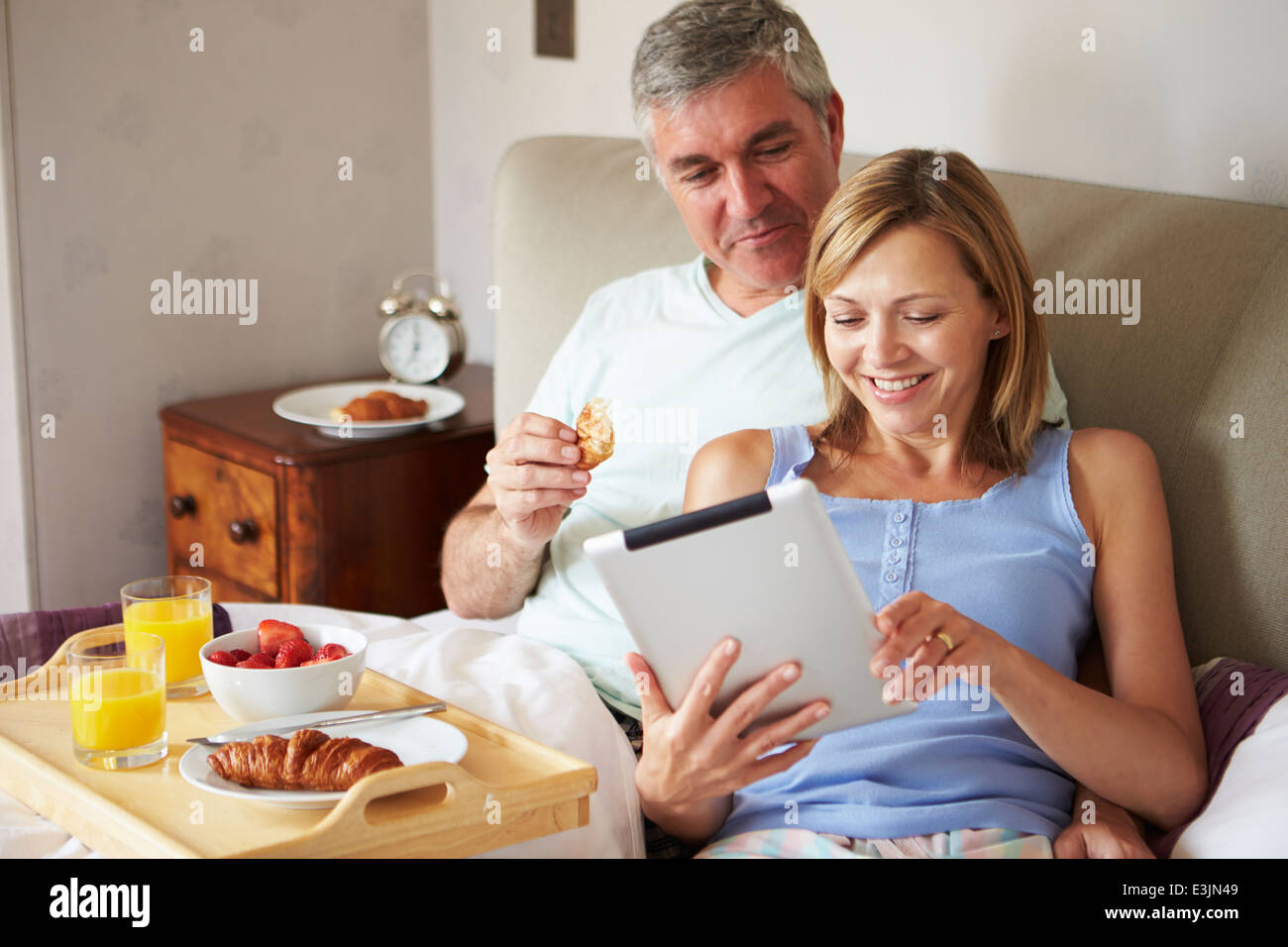 Couple Eating Breakfast In Bed avec papier et digital Tablet Banque D'Images