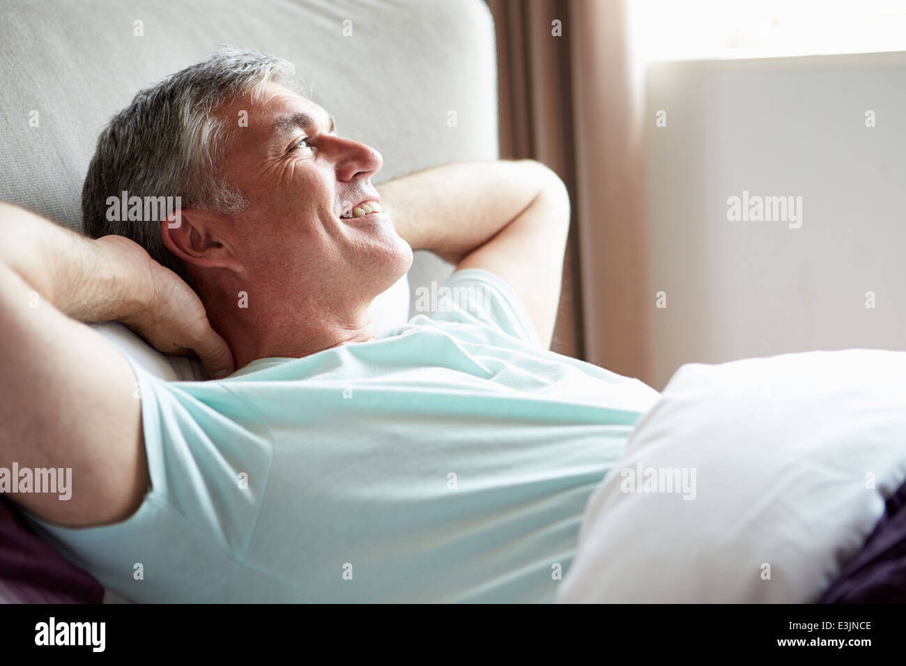 Middle aged Man Waking Up In Bed Banque D'Images