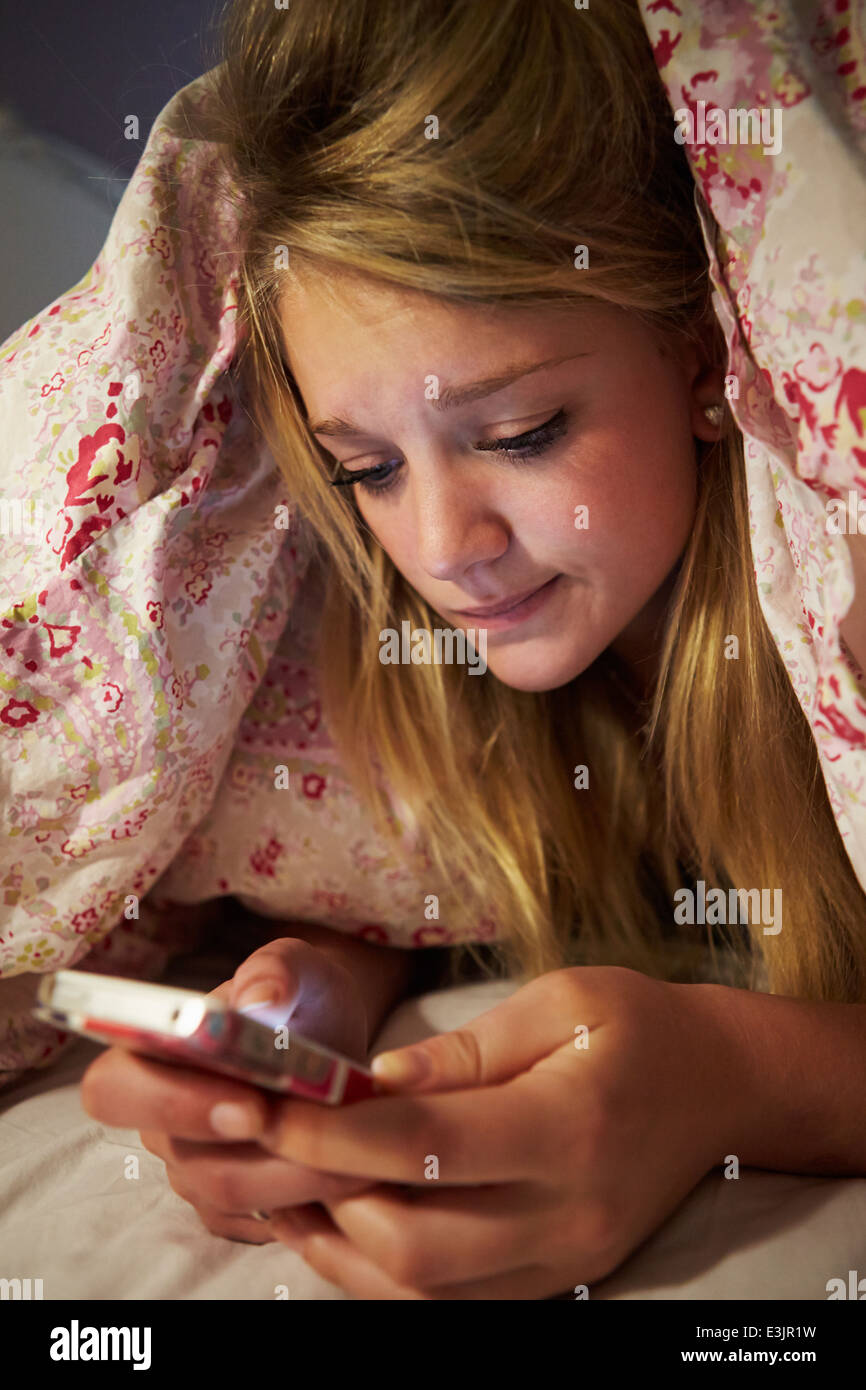 Adolescente malheureuse de l'envoi de message texte tout en Lying in Bed Banque D'Images