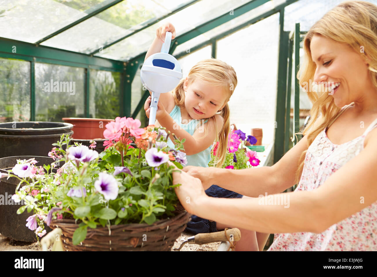 Mother and Daughter Watering Plants in Greenhouse Banque D'Images