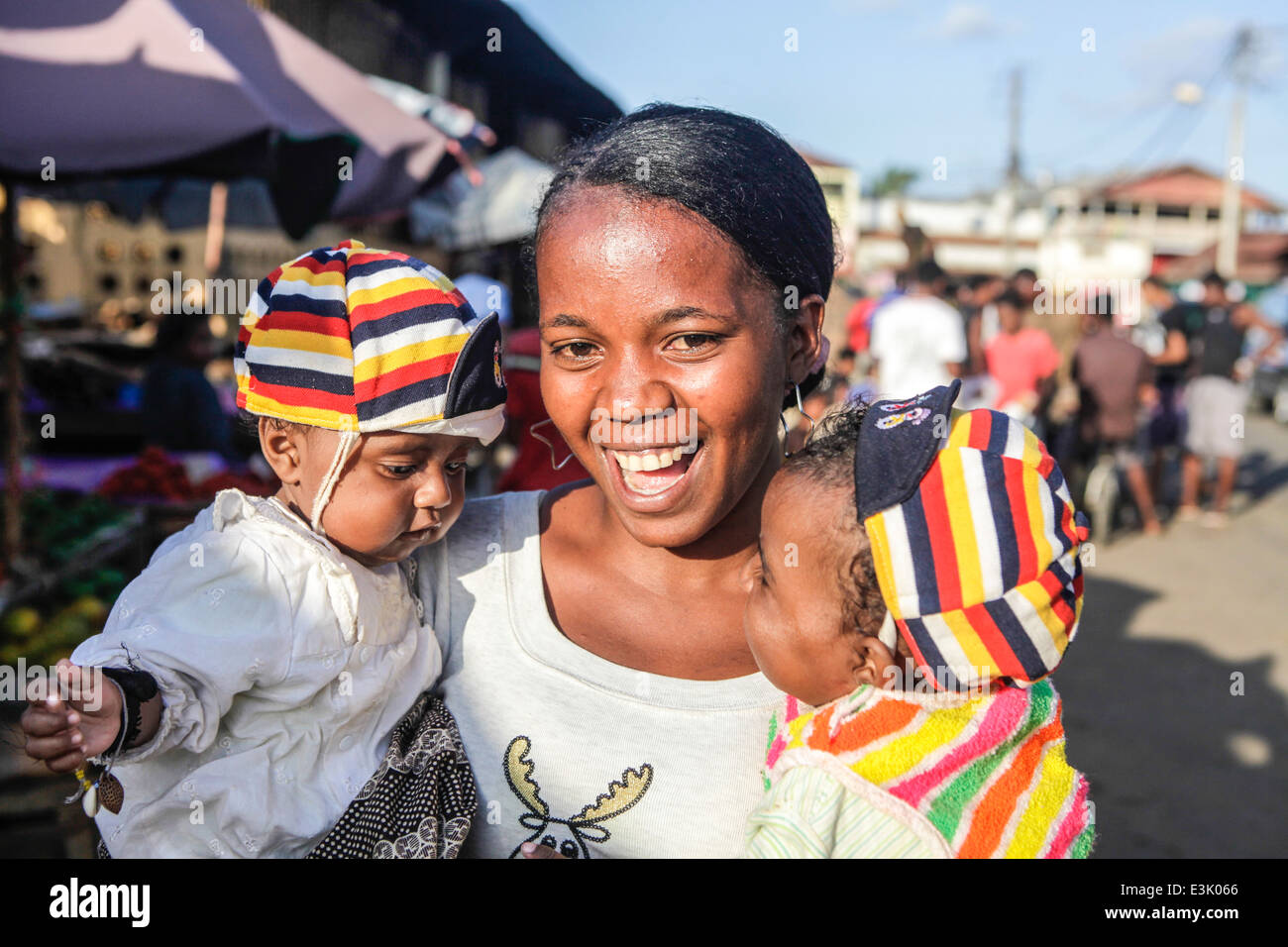 Femme souriante avec deux enfants à un marché alimentaire à Madagascar Banque D'Images