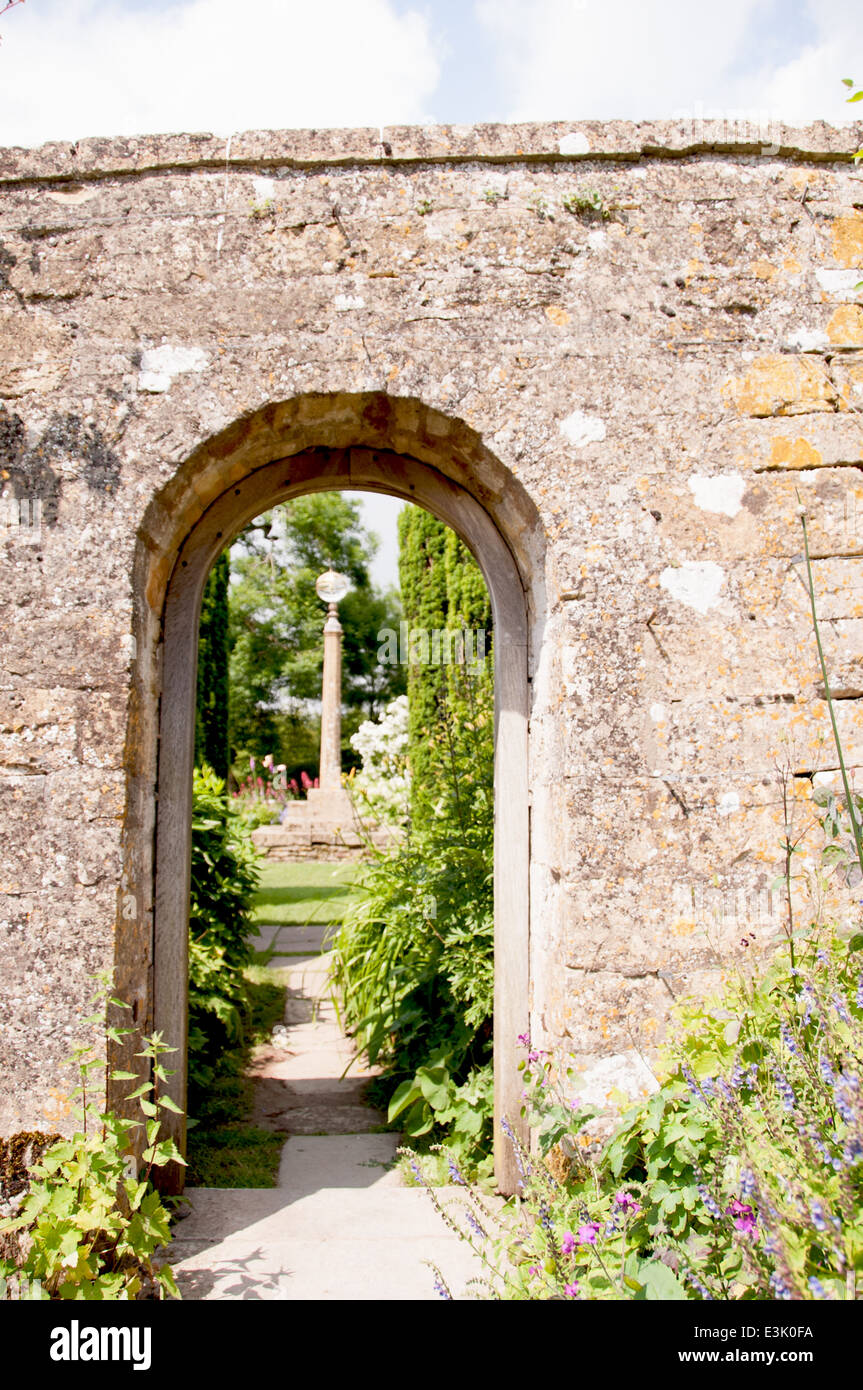 Regarder à travers une porte de pierre dans un jardin secret d'une maison de campagne anglaise à l'été Banque D'Images