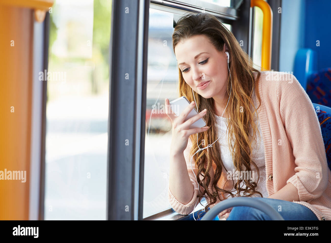 Young Woman Wearing Earphones écouter de la musique sur le bus Banque D'Images