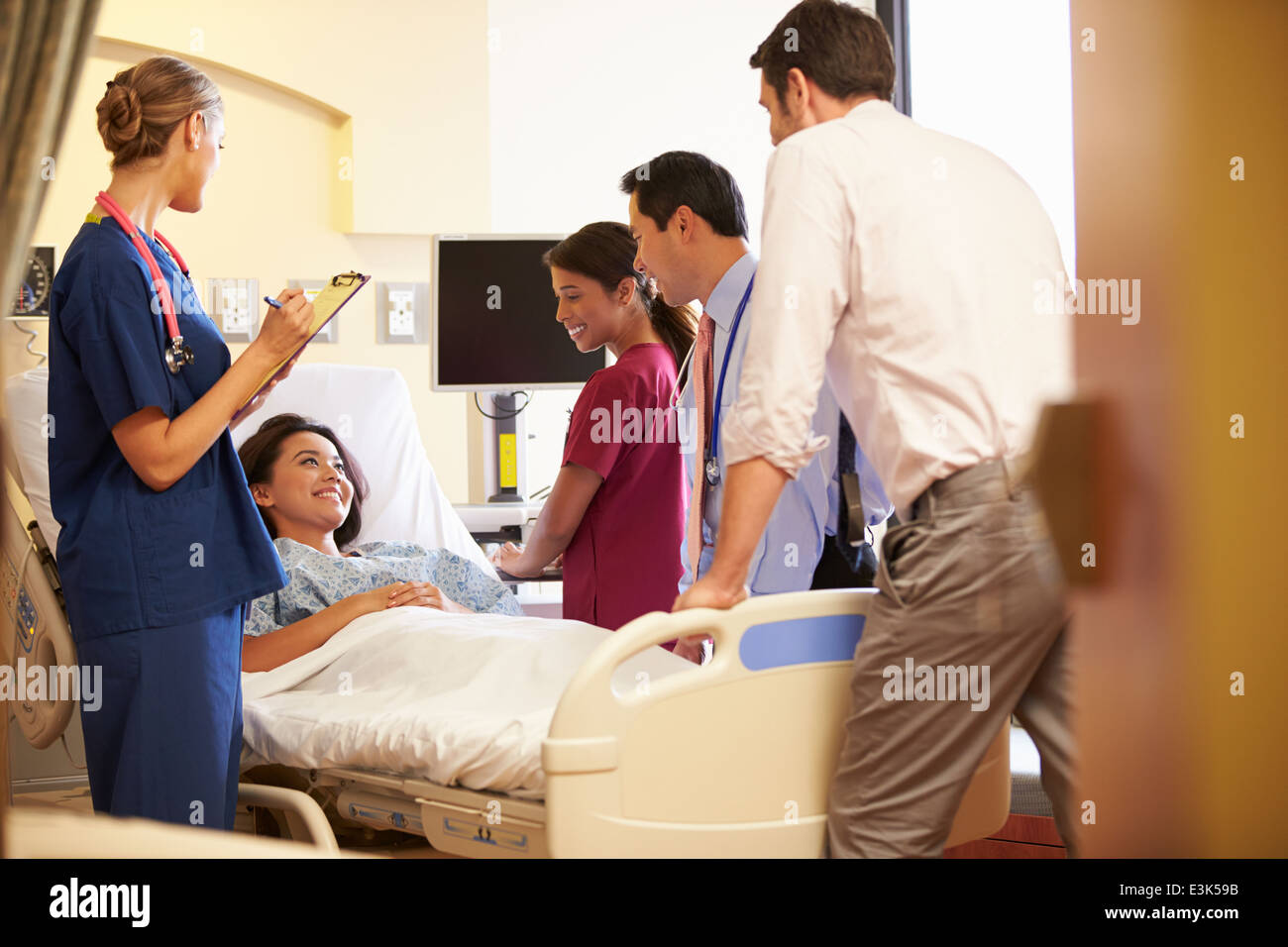 Réunion de l'équipe médicale autour de Female Patient In Hospital Room Banque D'Images