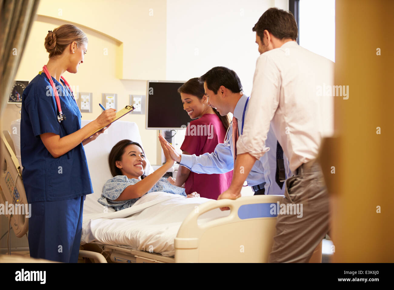 Réunion de l'équipe médicale autour de Female Patient In Hospital Room Banque D'Images