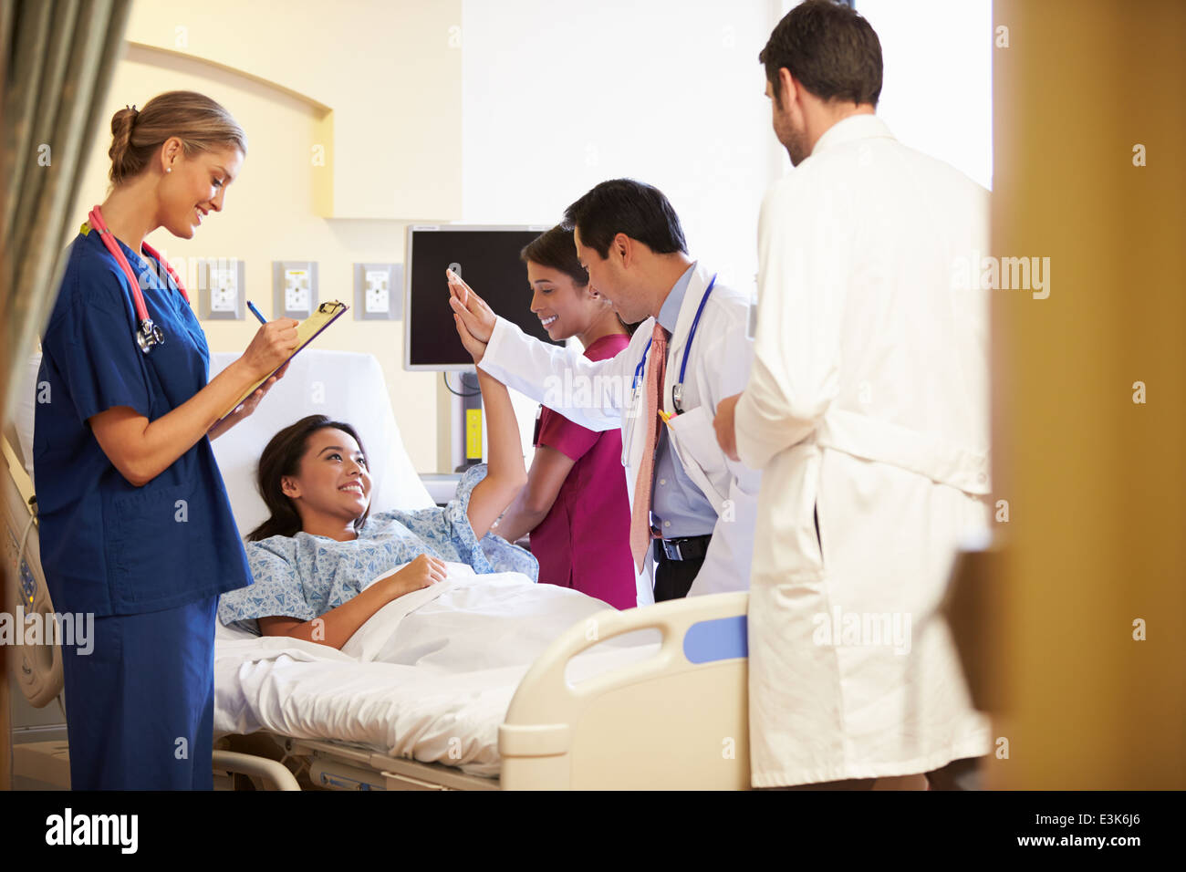 Réunion de l'équipe médicale autour de Female Patient In Hospital Room Banque D'Images