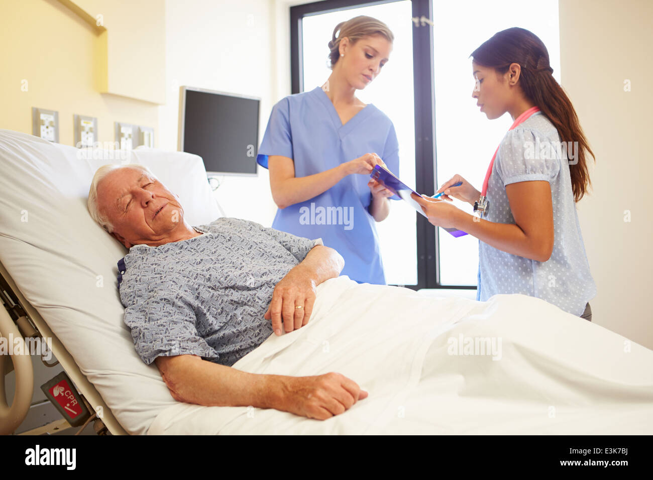 Réunion de l'équipe médicale en tant que Senior Man Sleeps in Hospital Room Banque D'Images