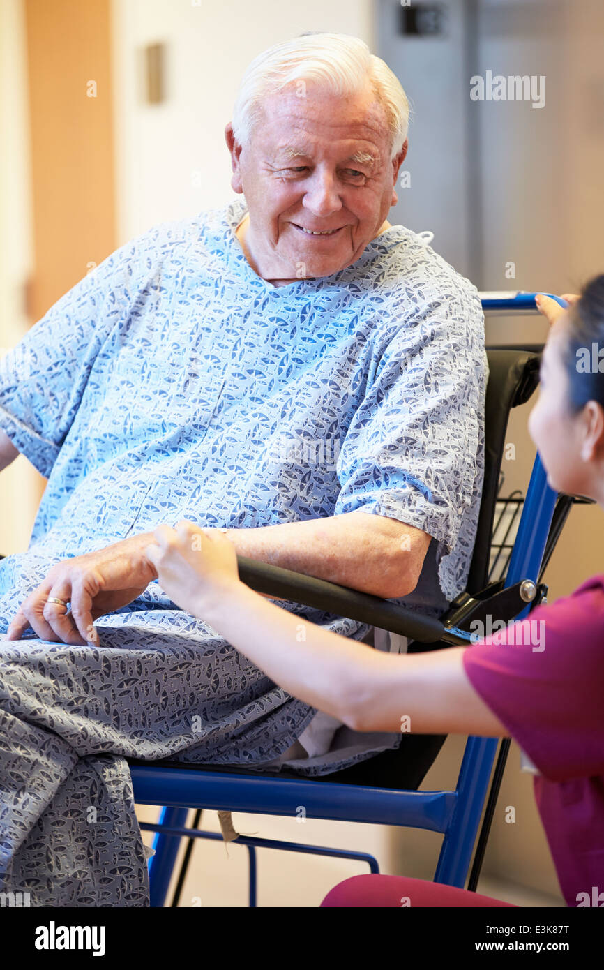 Senior Male Patient In Wheelchair poussés par des infirmières Banque D'Images