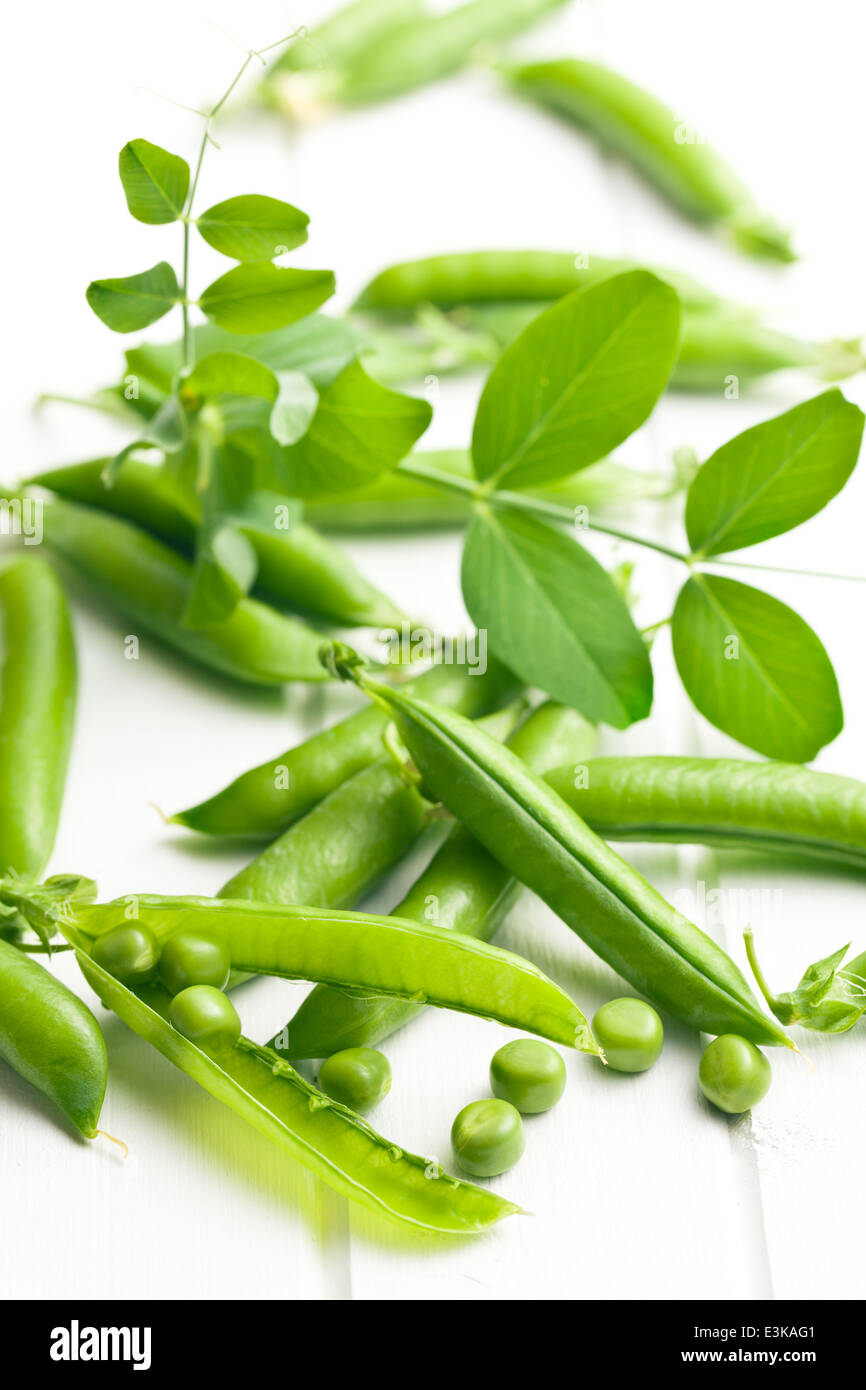 Gousse de pois vert sur blanc table table en bois Banque D'Images