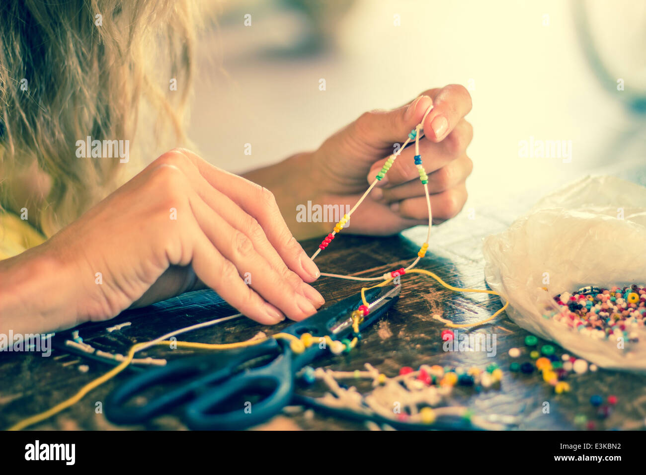 Des mains femme artisanat artisanat coloré bracelet passe-temps 'traverser' enfiler des perles perles d'acier Banque D'Images