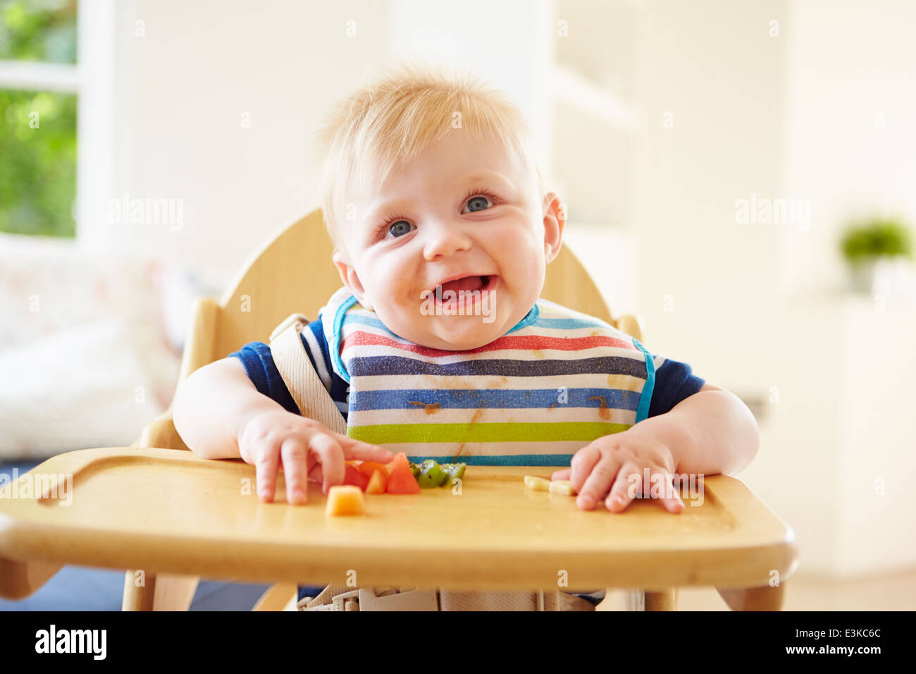 Baby Boy Eating Fruit dans une chaise haute Banque D'Images