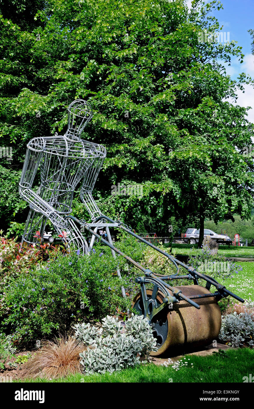Encadrée de sculpture fer M. Granger poussant une tondeuse sur le terrain de cricket de grange, Leominster, England, UK. Banque D'Images
