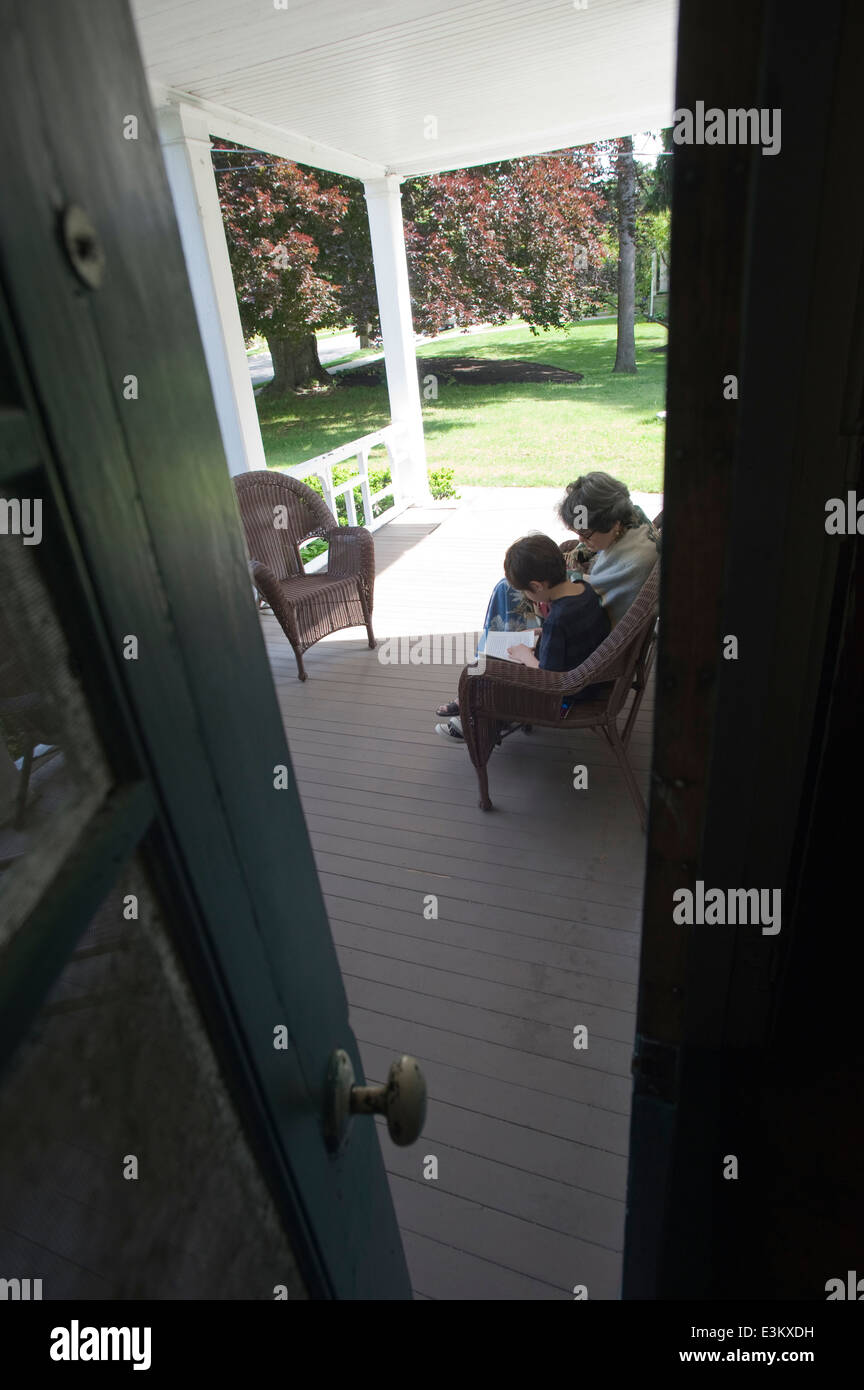 Grand-mère et de six (6) ans petit-fils caresser sur porche et lire une histoire Banque D'Images