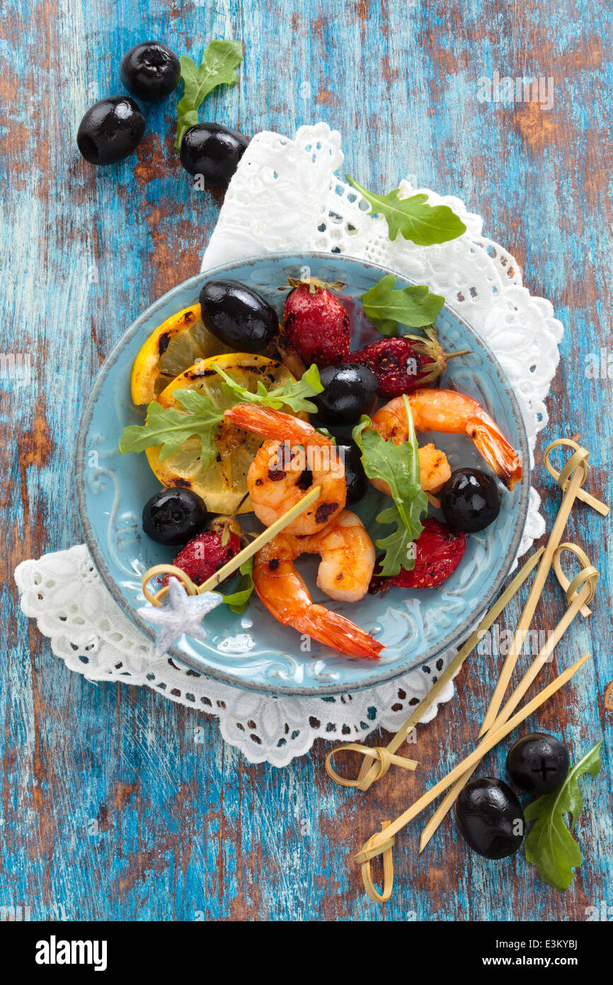 Crevettes grillées fruits et feuilles de roquette au fond rustique. Vue de dessus. Banque D'Images