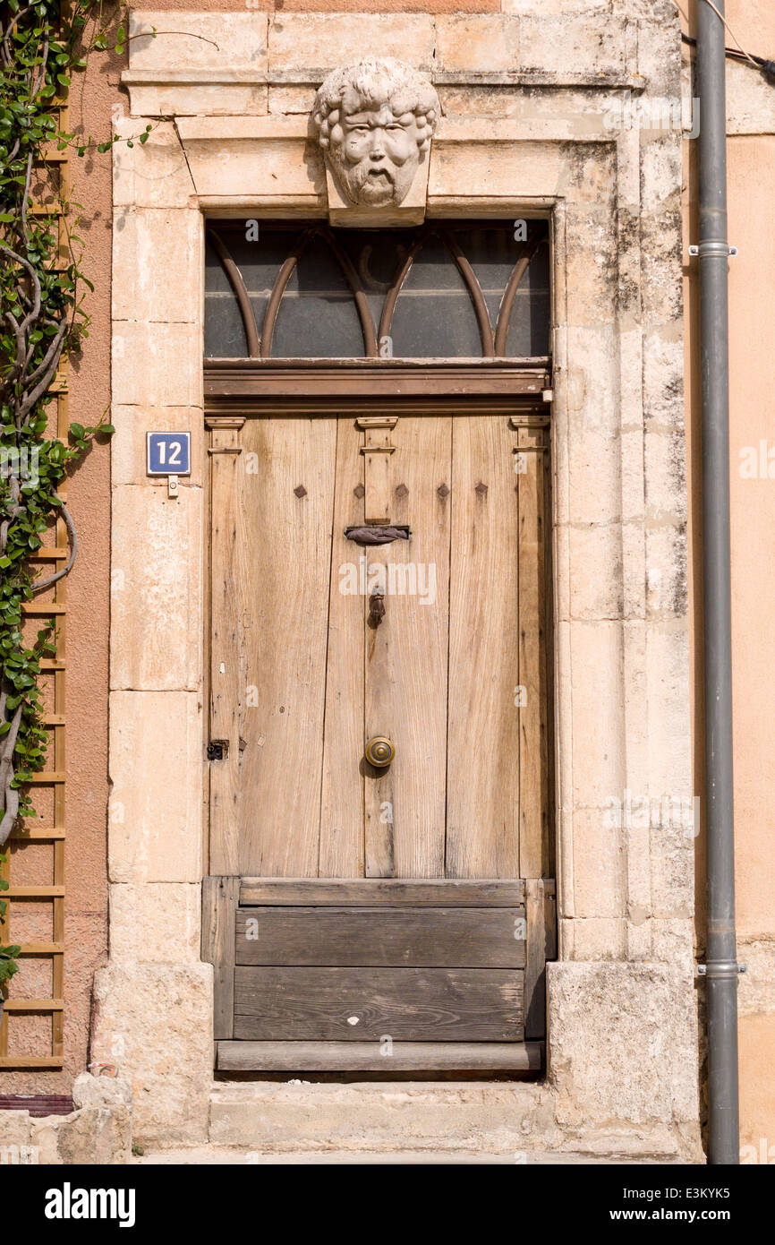 Porte en bois avec face Keystone, numéro 12. Une vieille porte en bois non peint et patché avec un visage moulé qui en est la pierre angulaire. Banque D'Images