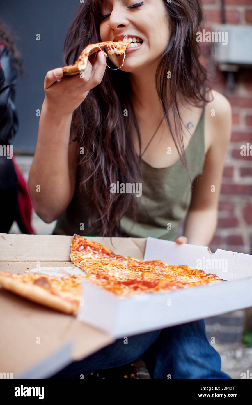 Young adult woman eating pizza Banque D'Images