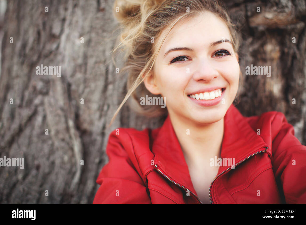 Portrait of smiling woman (18-19) contre l'arbre Banque D'Images