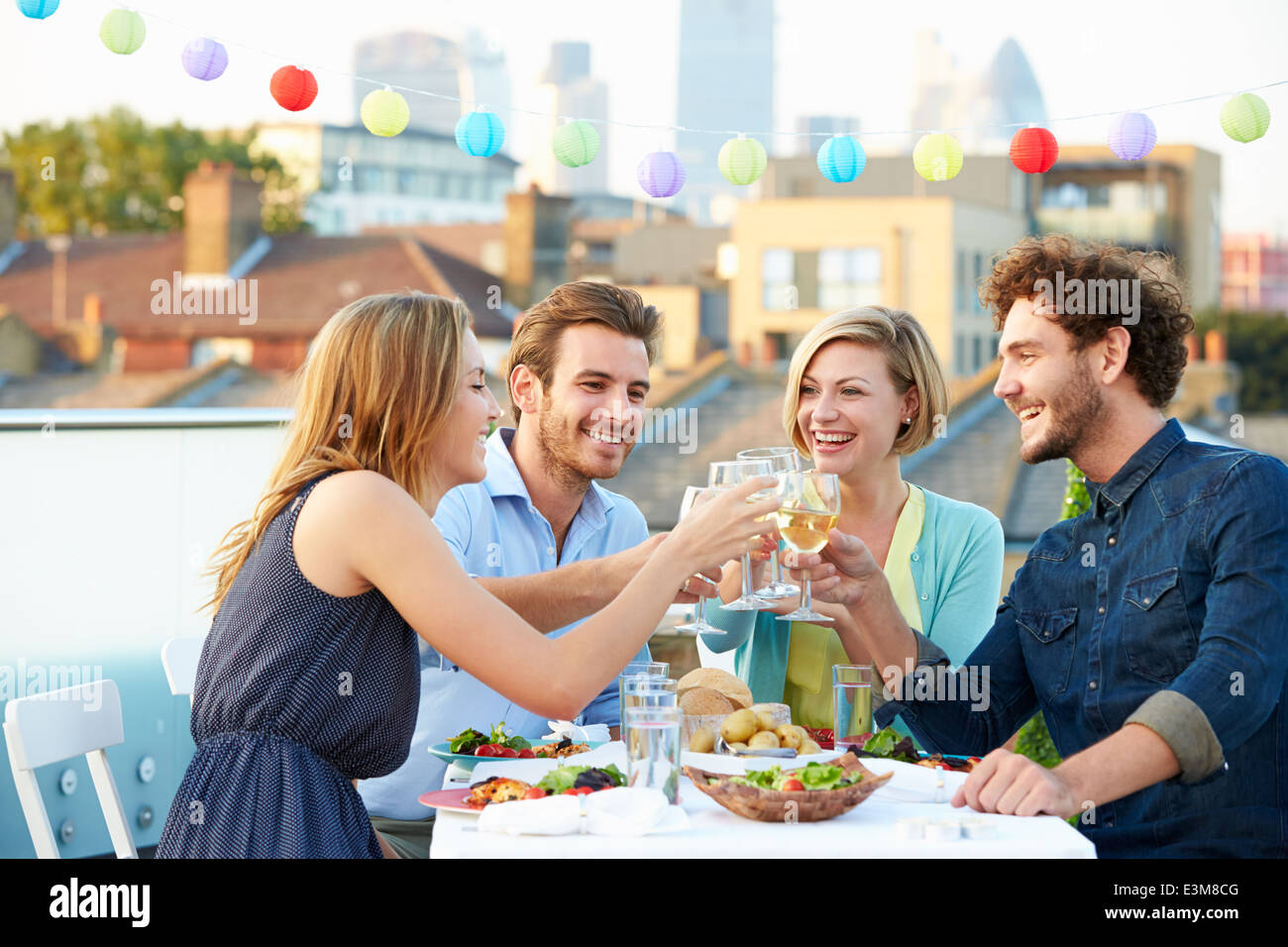 Groupe d'amis manger repas sur terrasse sur le toit Banque D'Images
