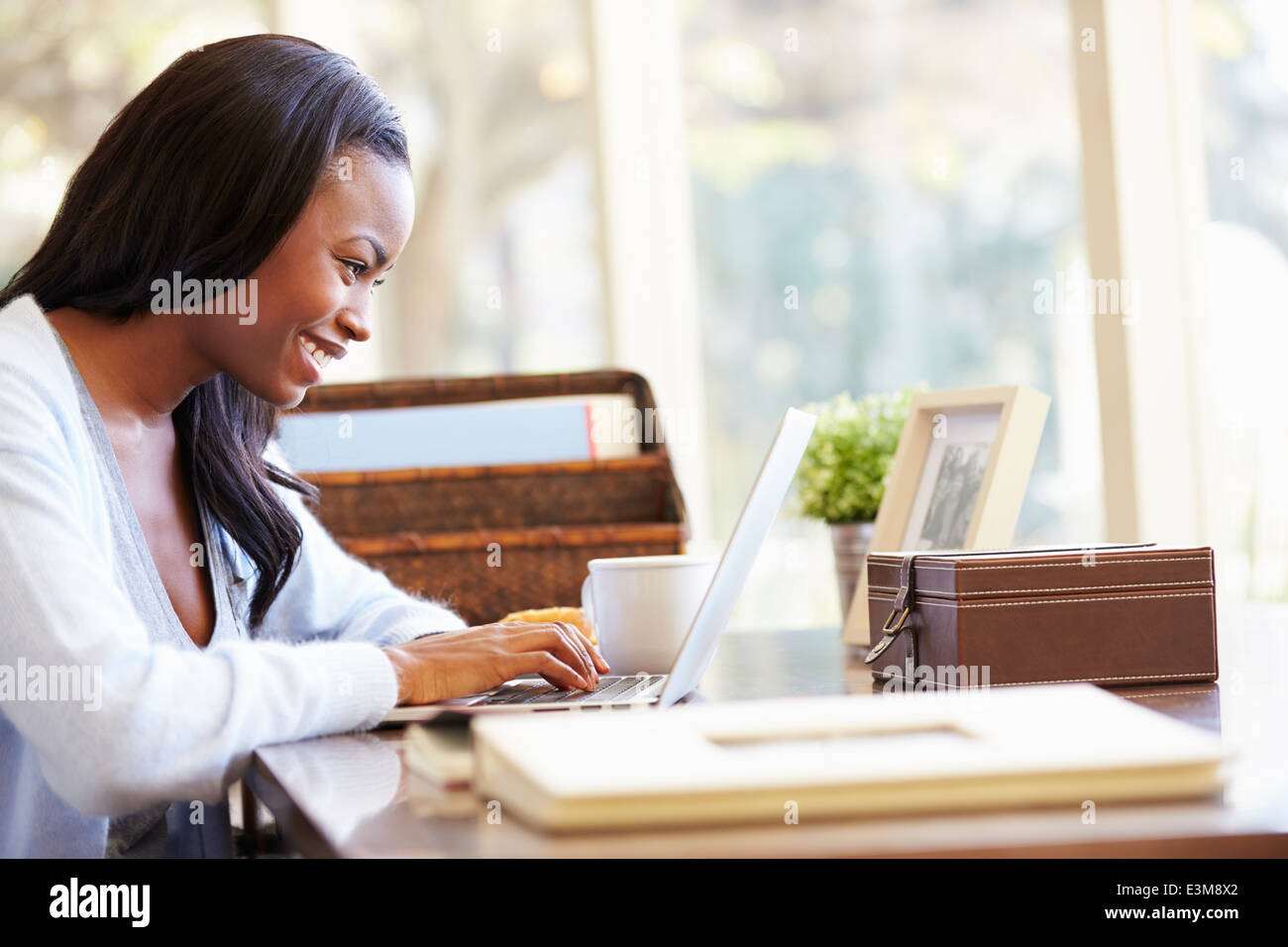 Femme à l'aide d'un ordinateur portable sur un bureau à la maison Banque D'Images
