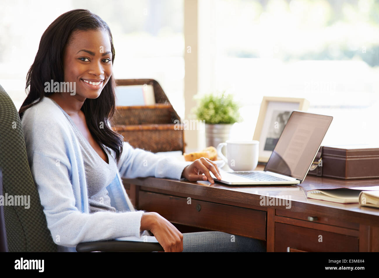 Femme à l'aide d'un ordinateur portable sur un bureau à la maison Banque D'Images
