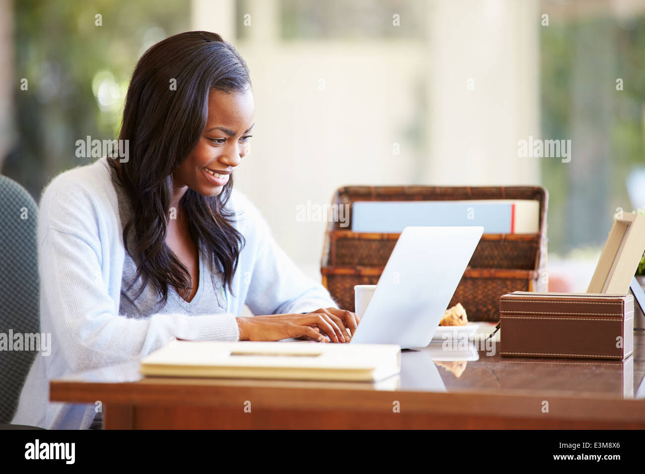 Femme à l'aide d'un ordinateur portable sur un bureau à la maison Banque D'Images