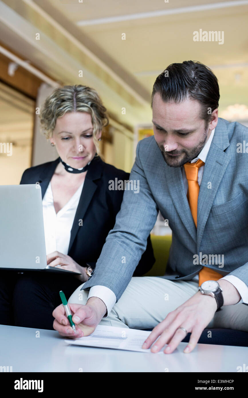 Young businesswoman looking at collègue masculin signature document in office Banque D'Images