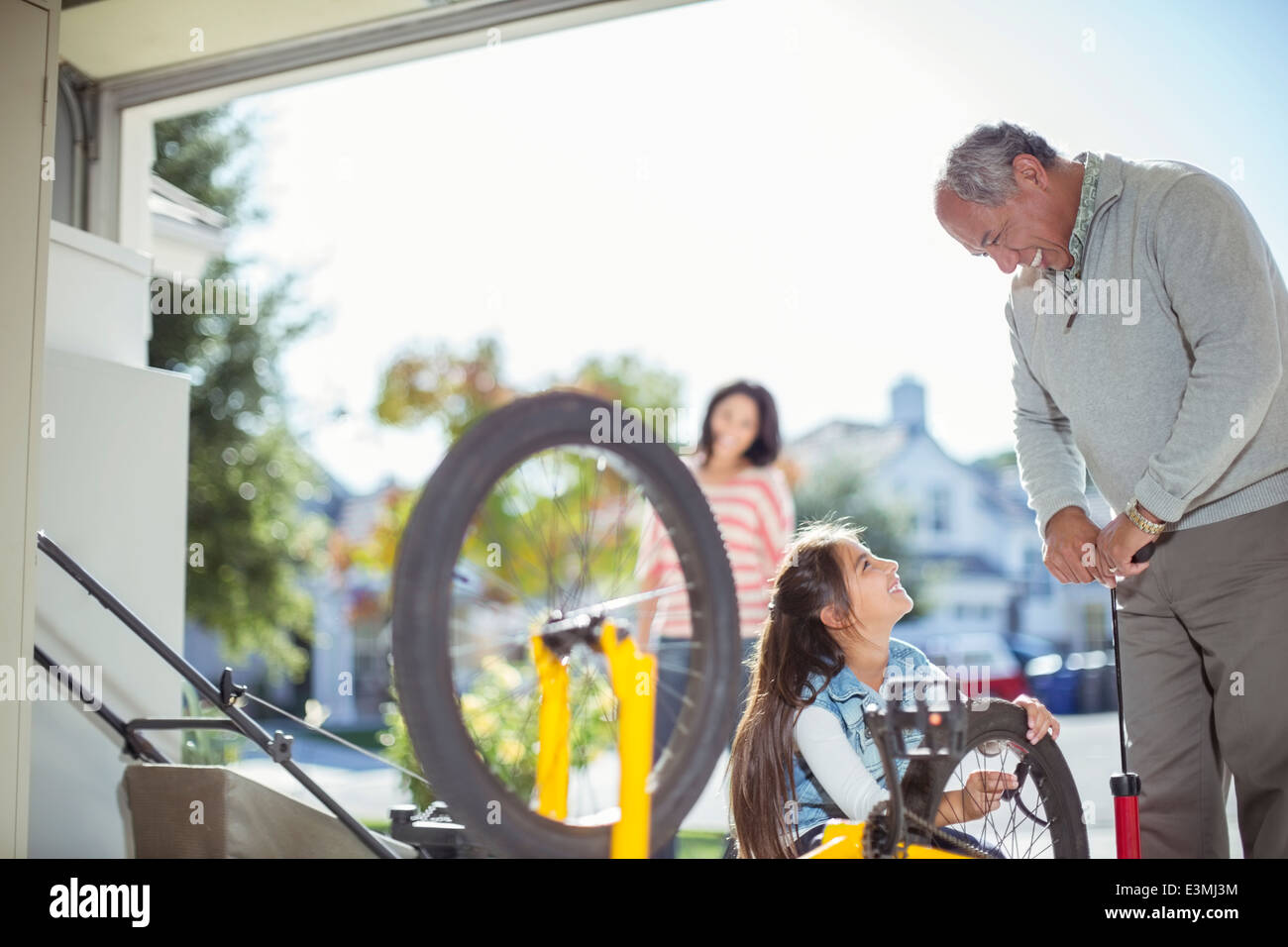 Grand-père et petite-fille du gonflage des pneus de vélo dans garage Banque D'Images