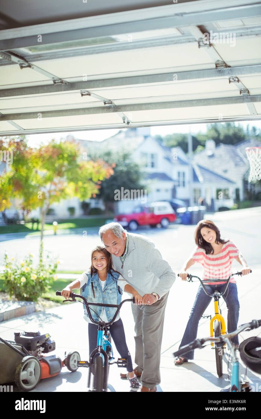 Multi-generation family riding bicycles in driveway Banque D'Images