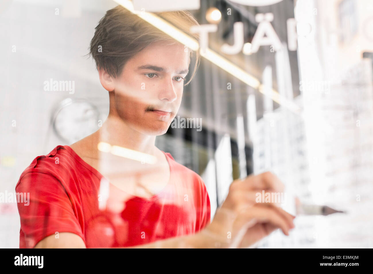 Jeune homme d'écrire sur du verre transparent au nouveau bureau Banque D'Images