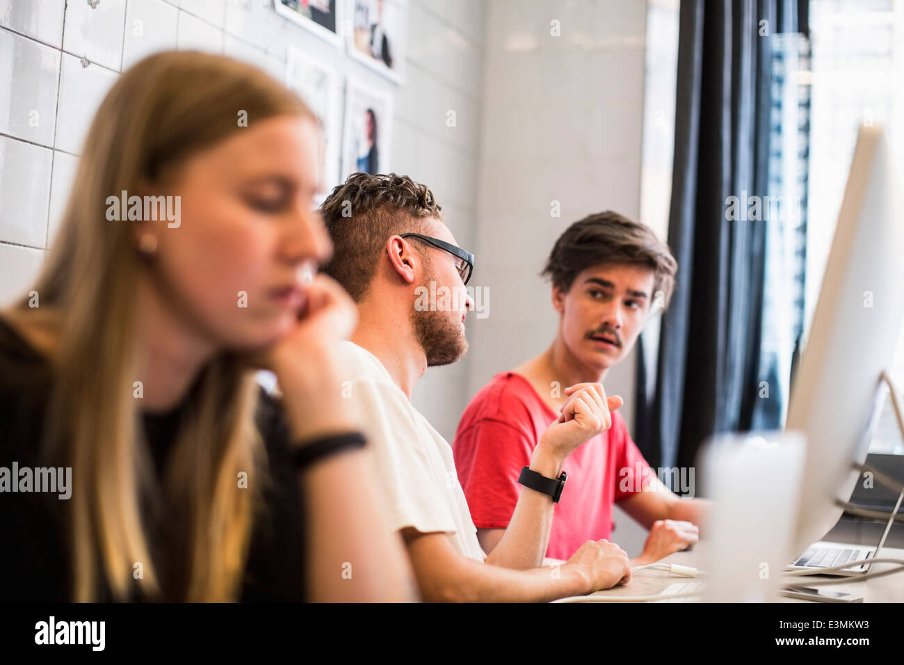 Les jeunes businessmen discussing with female colleague working en premier plan au nouveau bureau Banque D'Images